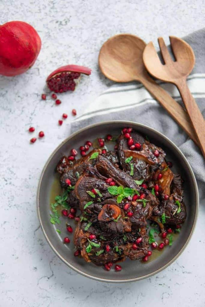 plate with lamb shoulder chops spoon and pomegranate