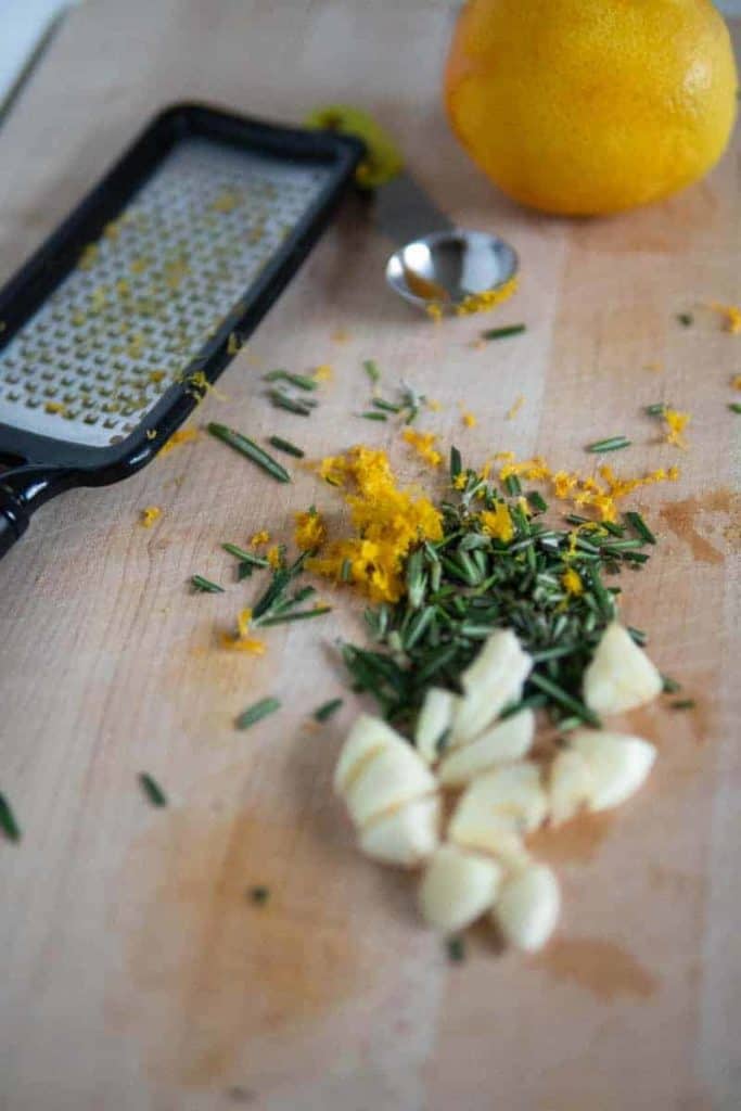 orange zest, rosemary and chopped garlic on cutting board