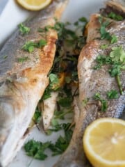 whole roasted branzino on a platter with lemons