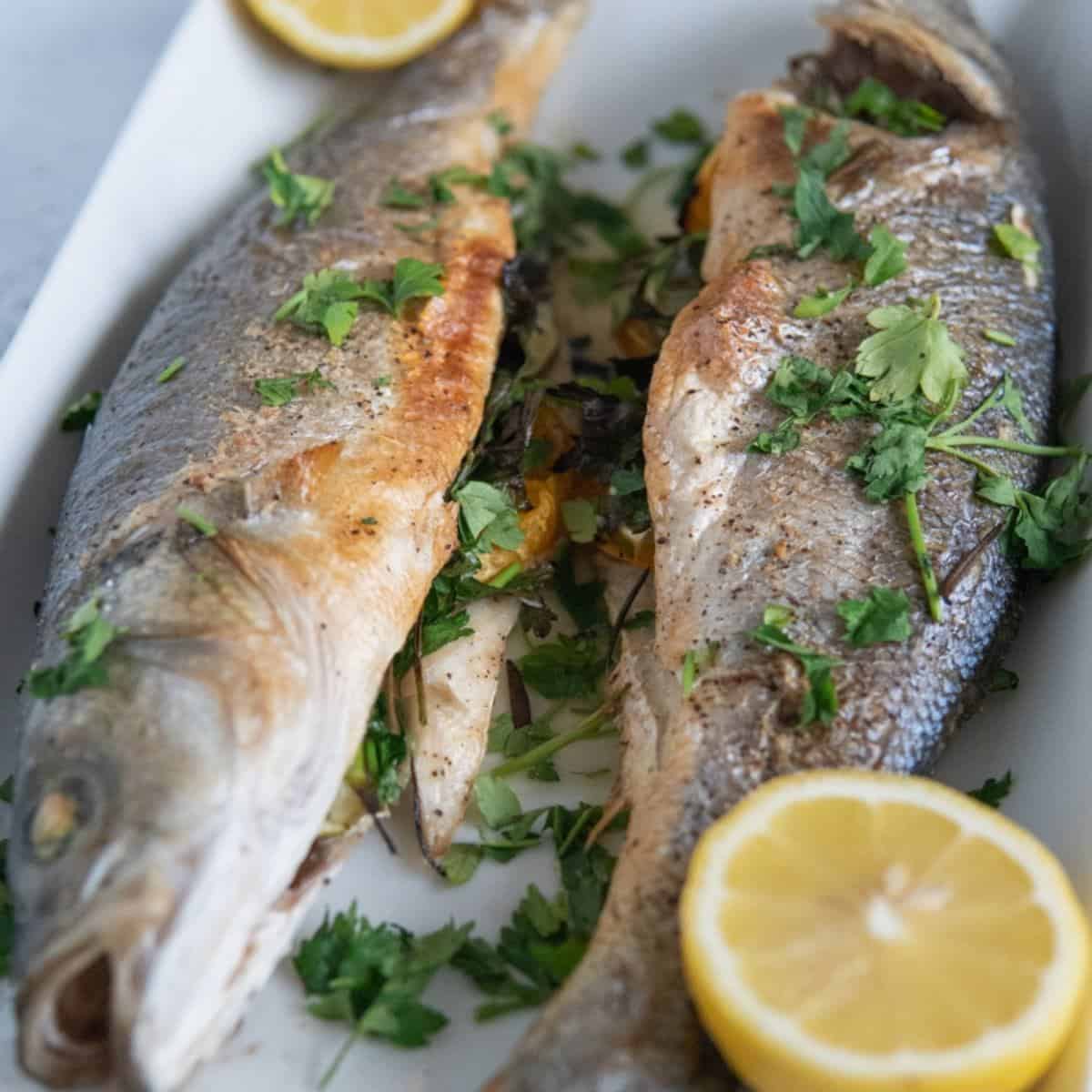 whole roasted branzino on a platter with lemons