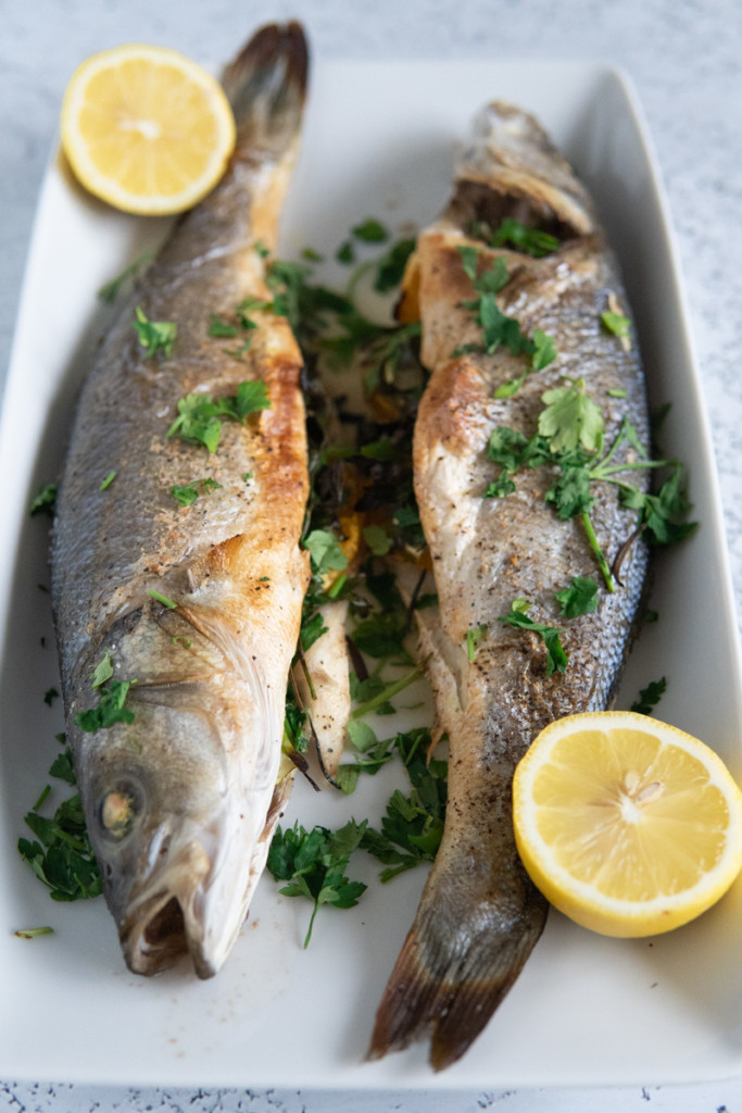 roasted fish on a platter with lemons 