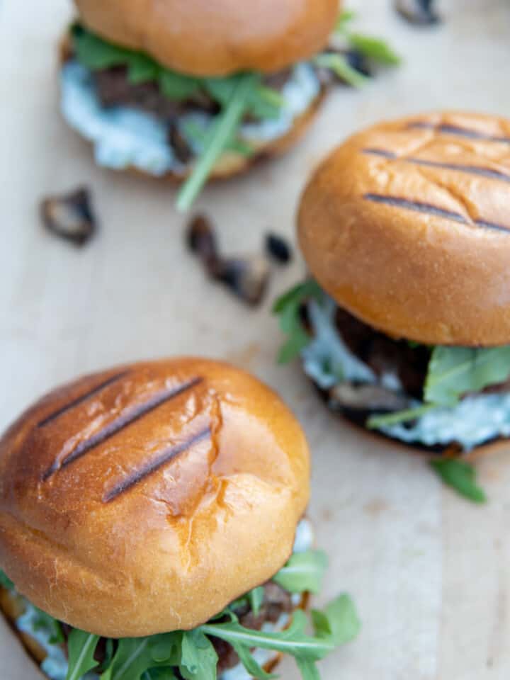 grilled lamb burgers with buns on a board