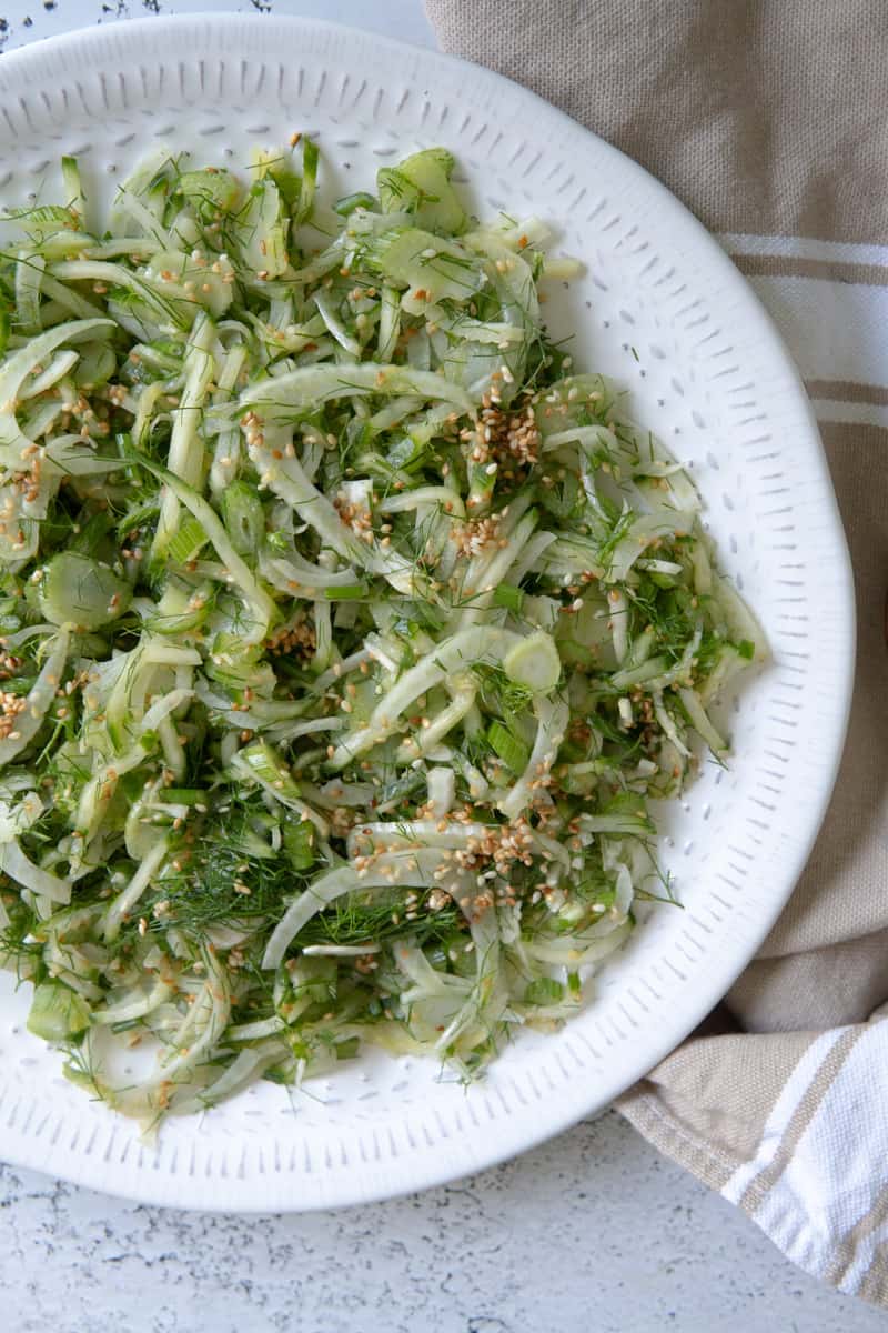 fennel salad with cucumber and sesame seeds on a white plate.