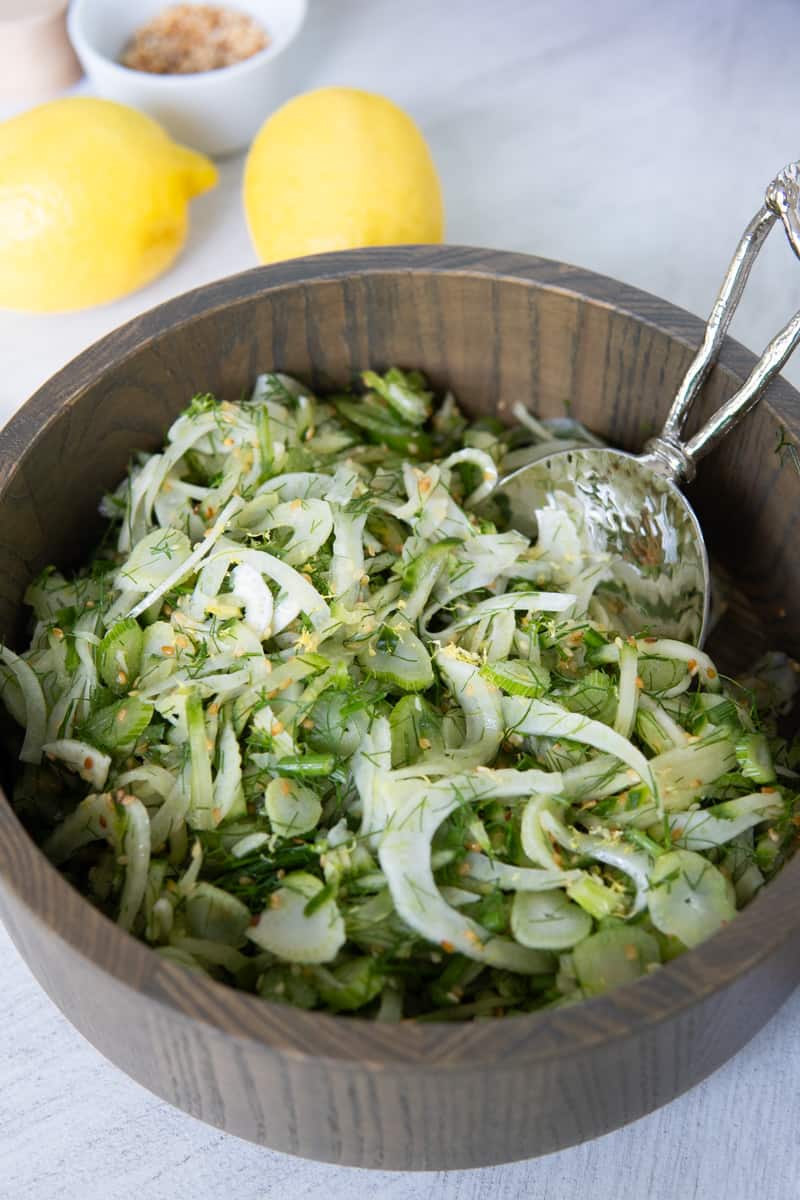 Bowl of cucumber and fennel salad topped with sesame seeds and lemon zest.