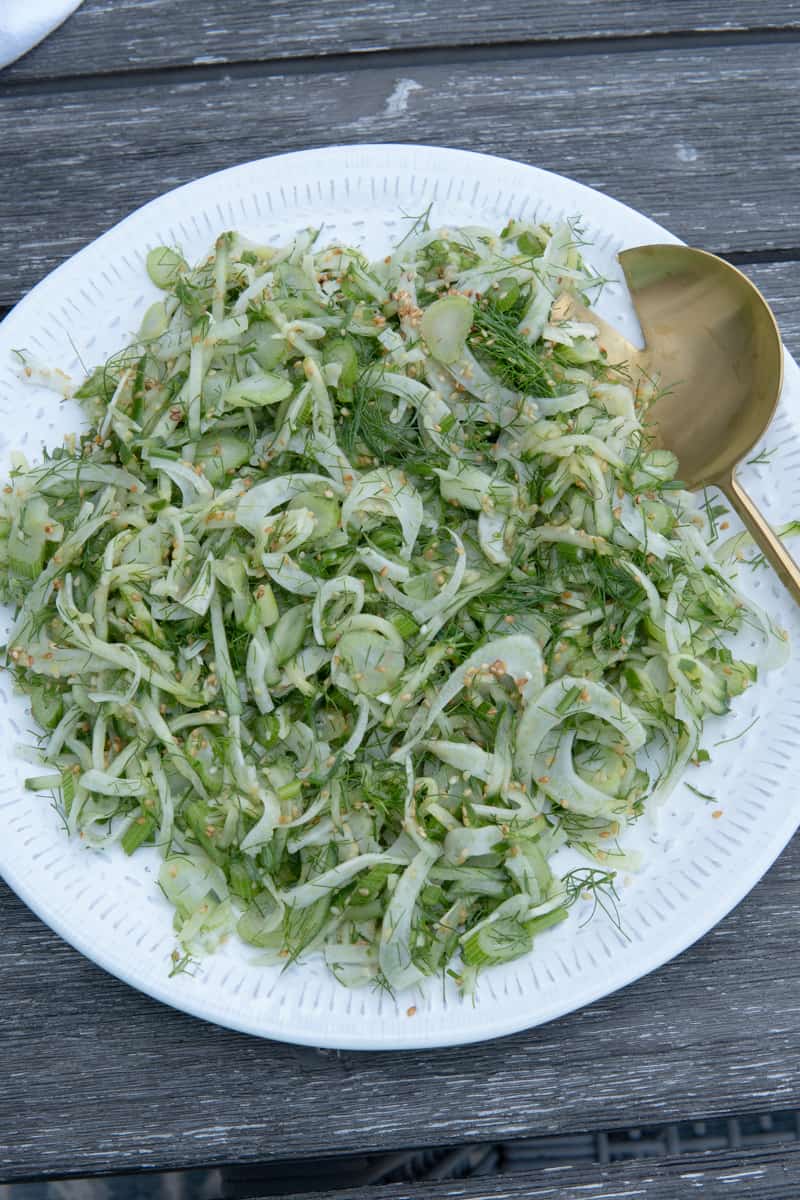 Cucumber fennel salad on a plate with a serving spoon.