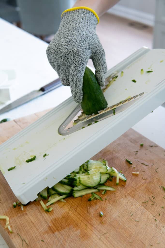 Slicing a cucumber on a mandoline.