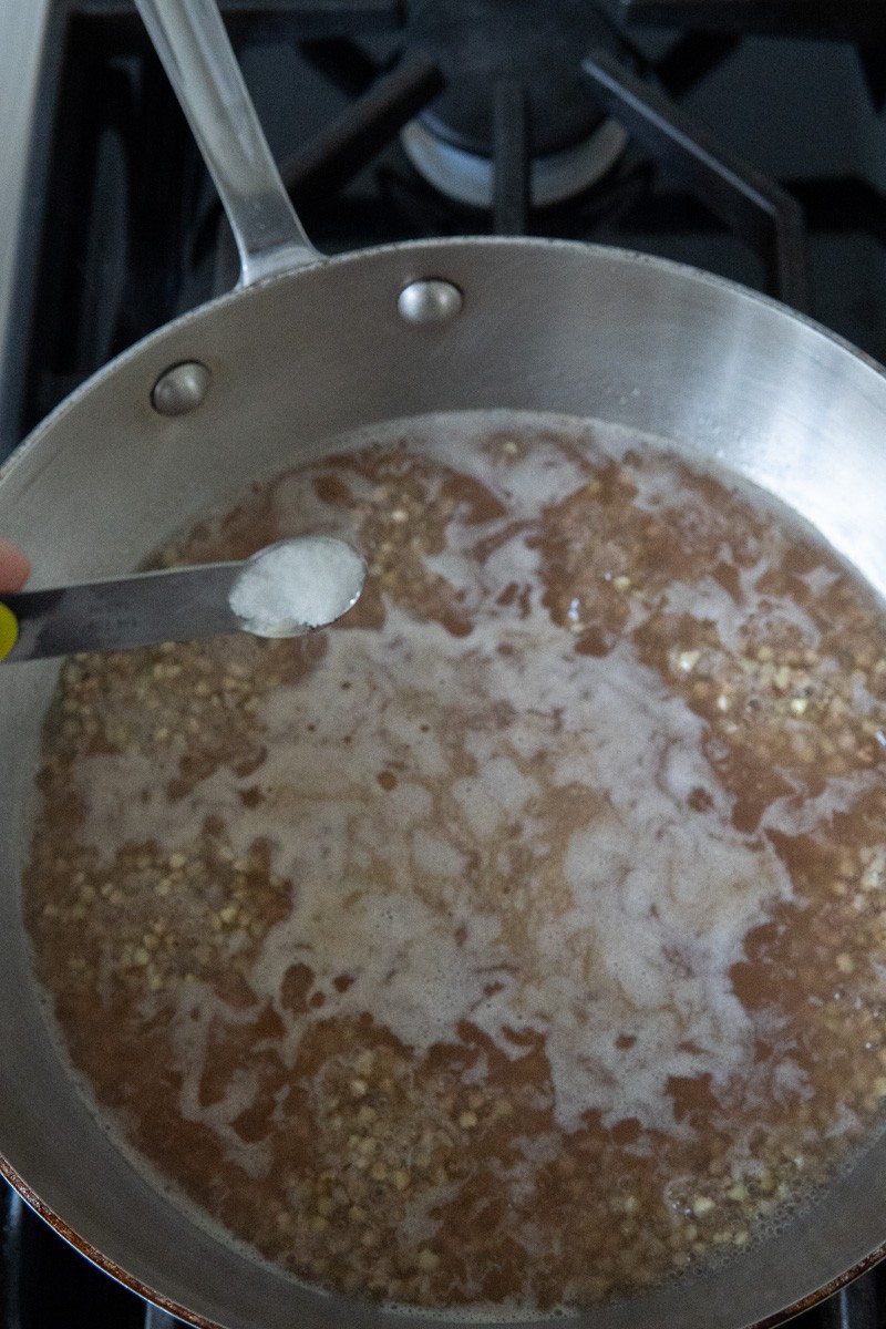 Adding salt to boiling buckwheat.
