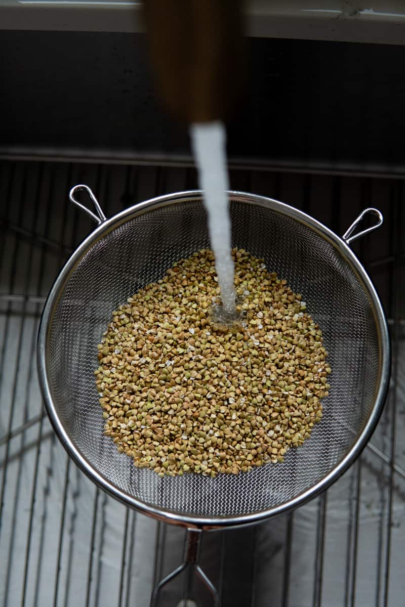 Rinsing buckwheat groats in a fine mesh strainer.