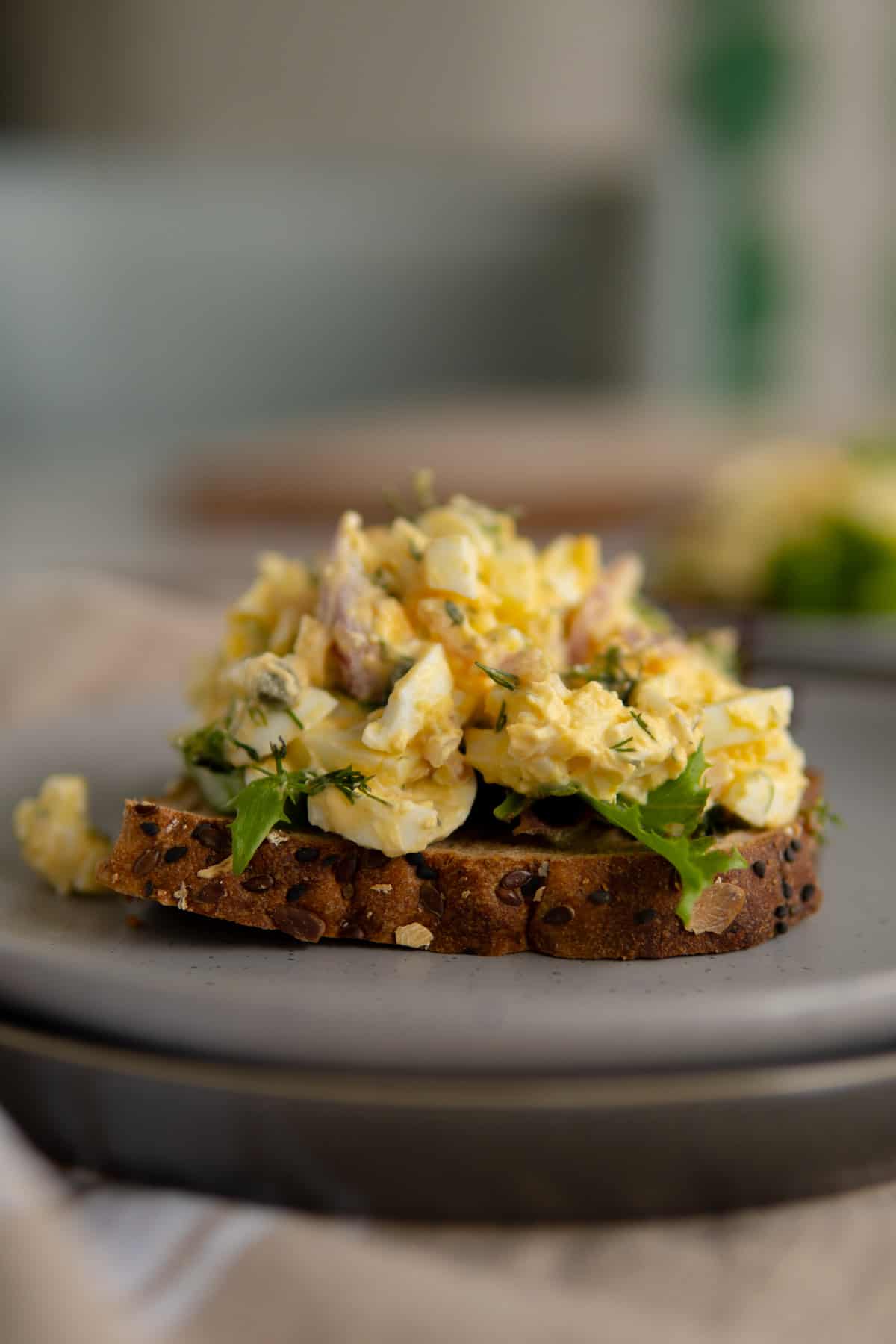 egg salad on top of a toast with some greens. 