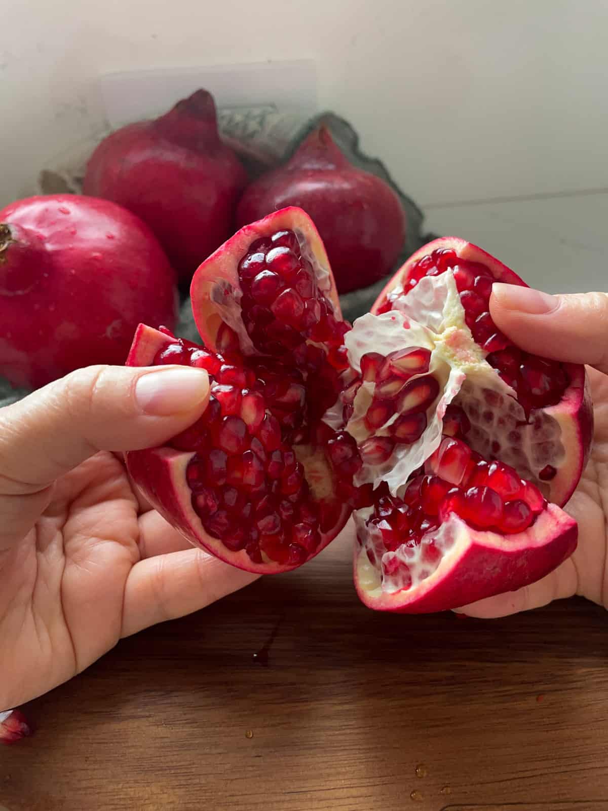 Pulling the segments of a pomegranate apart showing the arils inside.