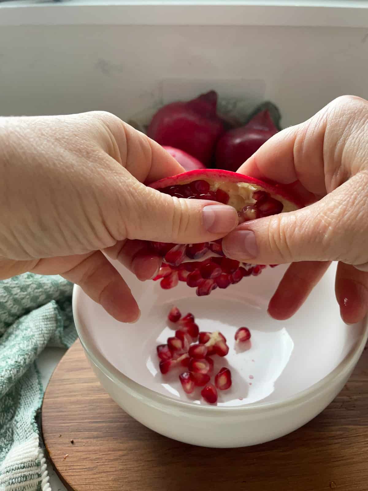 Loosening pomegranate seeds into a bowl.