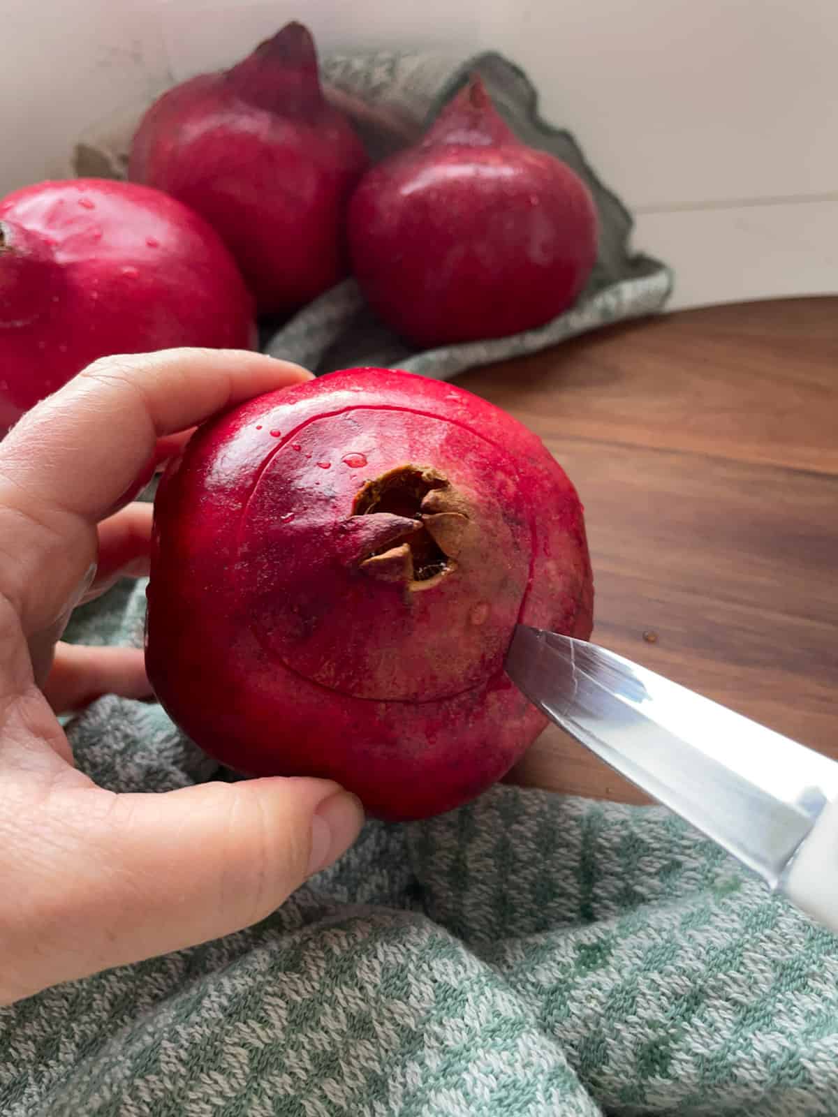 Scoring the top of a pomegranate with a paring knife.