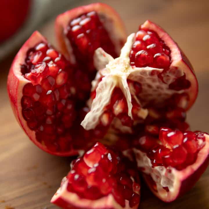 a cut open pomegranate revealing seeds and segments.