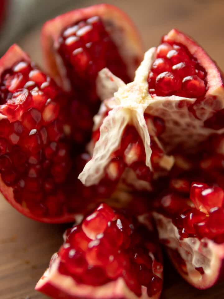 a cut open pomegranate revealing seeds and segments.