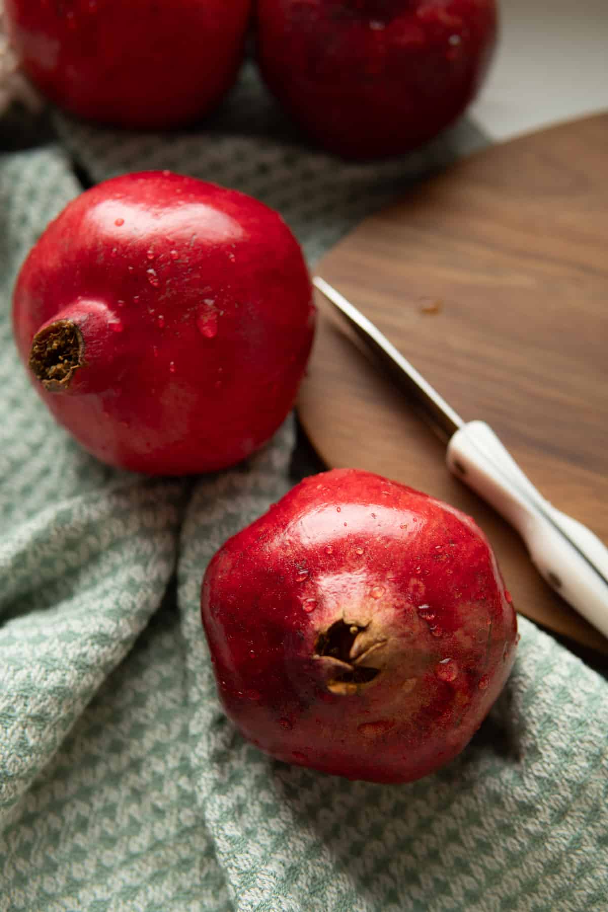 two whole pomegranates with a paring knife 