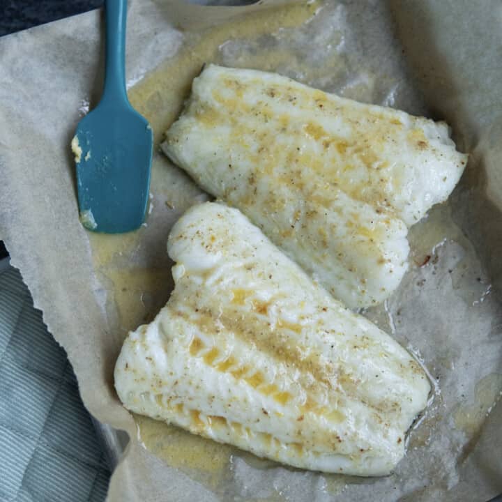 fish with melted compound butter on top of parchment paper