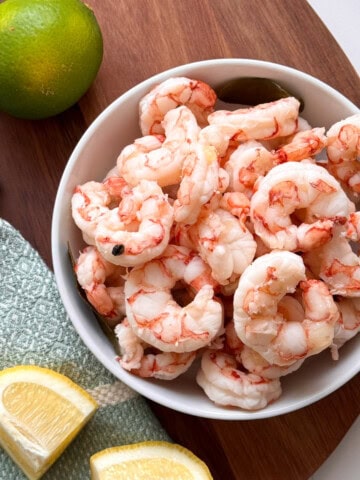 bowl with shrimp and lime and lemon wedges on side