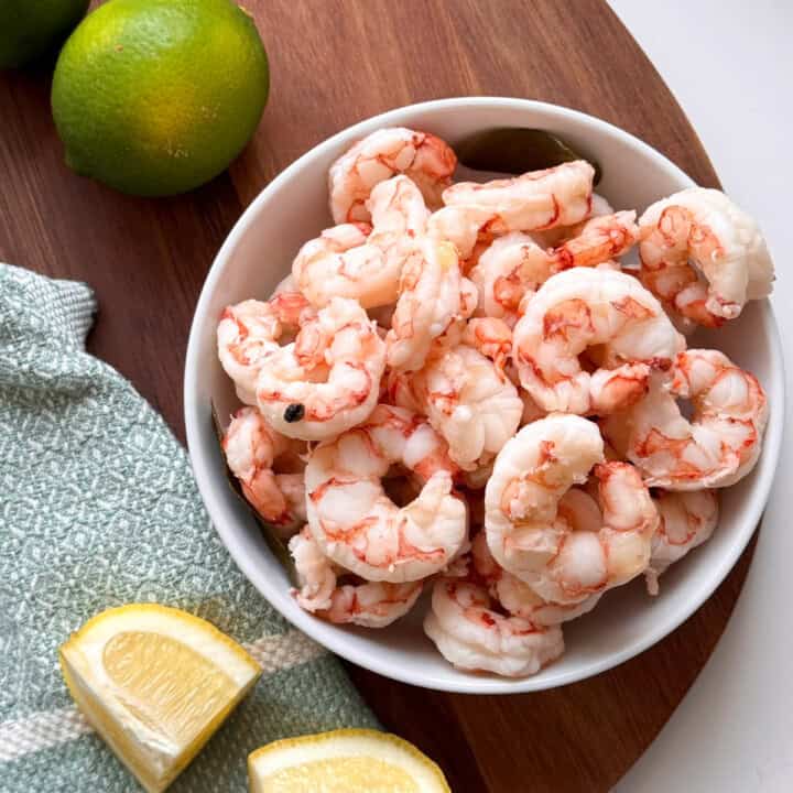 bowl with shrimp and lime and lemon wedges on side