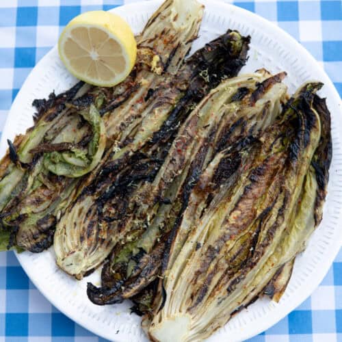 grilled romaine lettuce on a plate with lemon and spices
