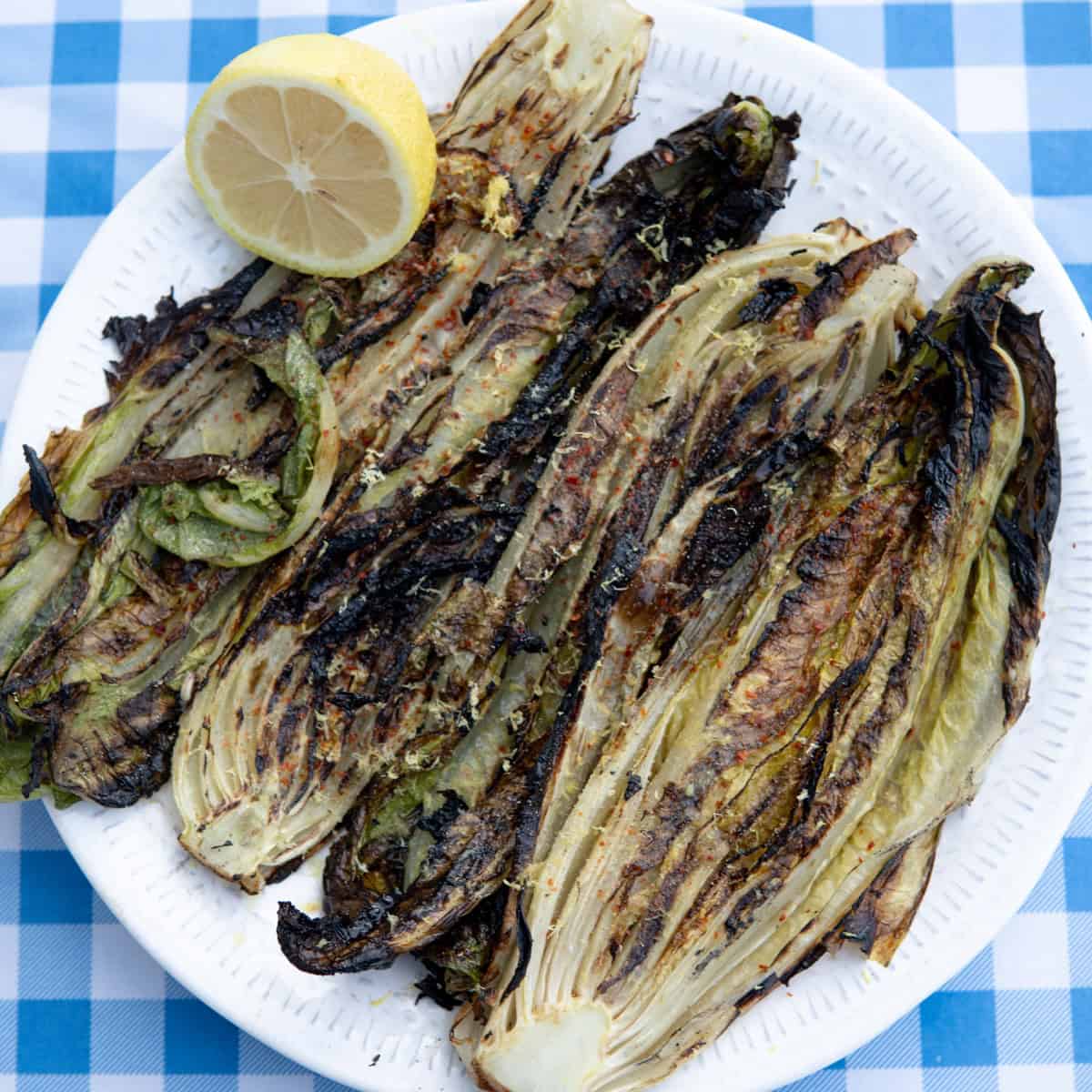 grilled romaine lettuce on a plate with lemon and spices