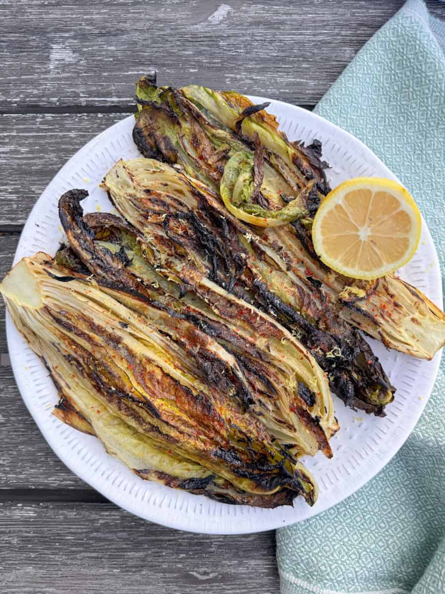 grilled romaine on a white plate with half a lemon