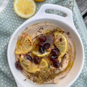 hummus in bowl with roasted lemons and olives