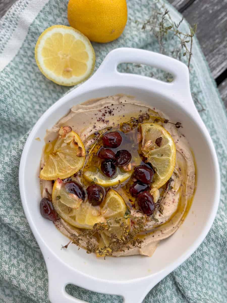 bowl with hummus, olive oil, lemons, olives 