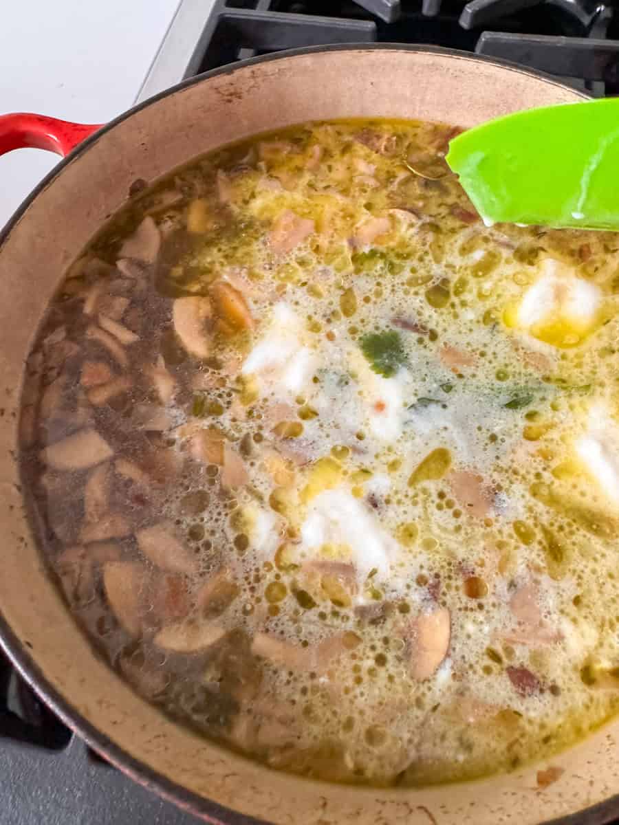 mushrooms cooking in broth in a dutch oven 