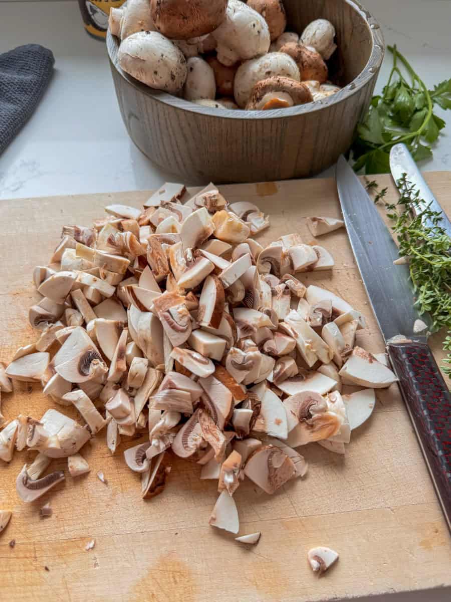 chopped up mushrooms on a wooden cutting board. 