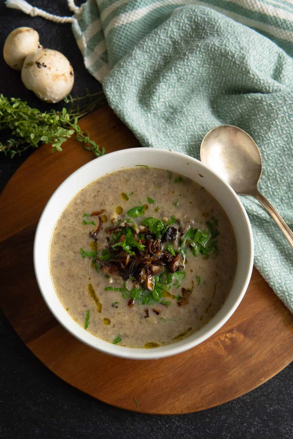 white bowl with pureed mushroom soup with a spoon on side