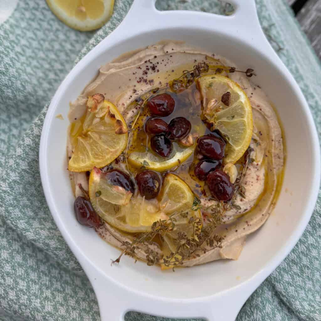 a bowl with hummus, olive oil, lemons and olives 