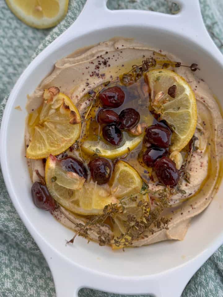 a bowl with hummus, olive oil, lemons and olives