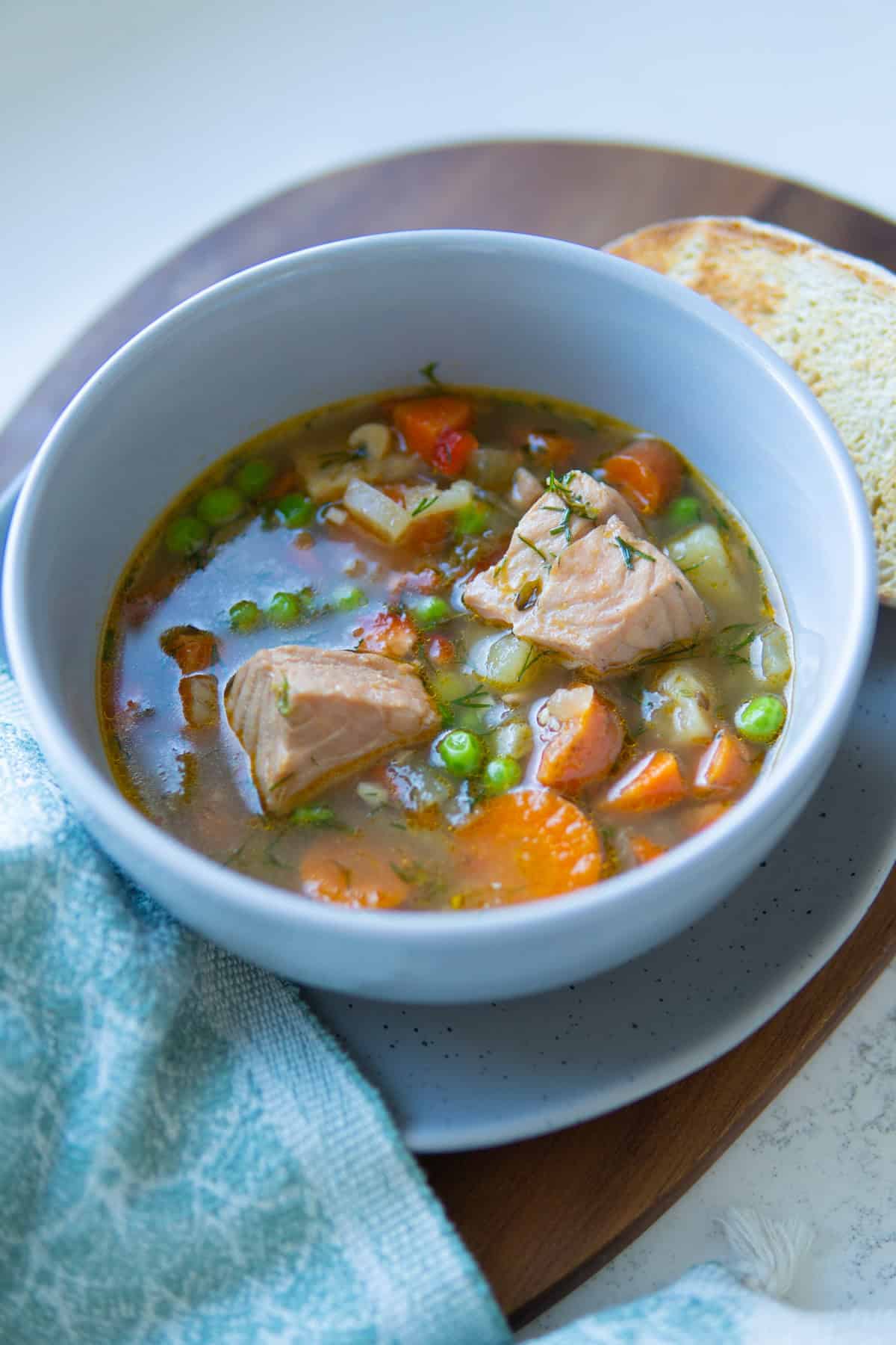 bowl with soup, salmon, peas and carrots