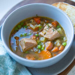 bowl of soup with peas, salmon chunks and carrots