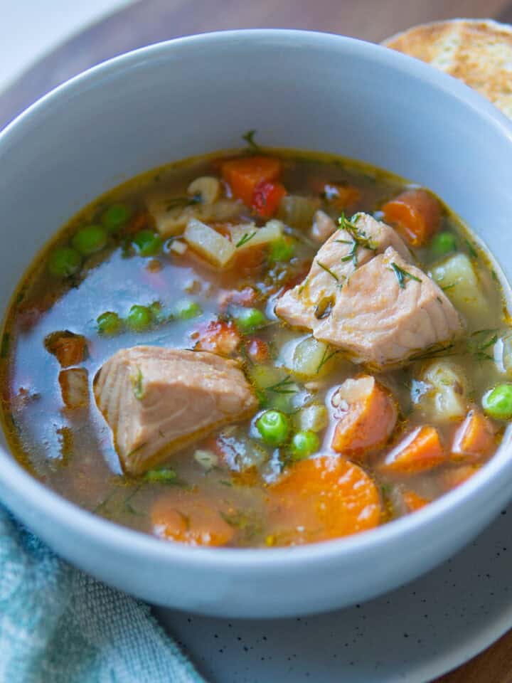 bowl of soup with peas, salmon chunks and carrots