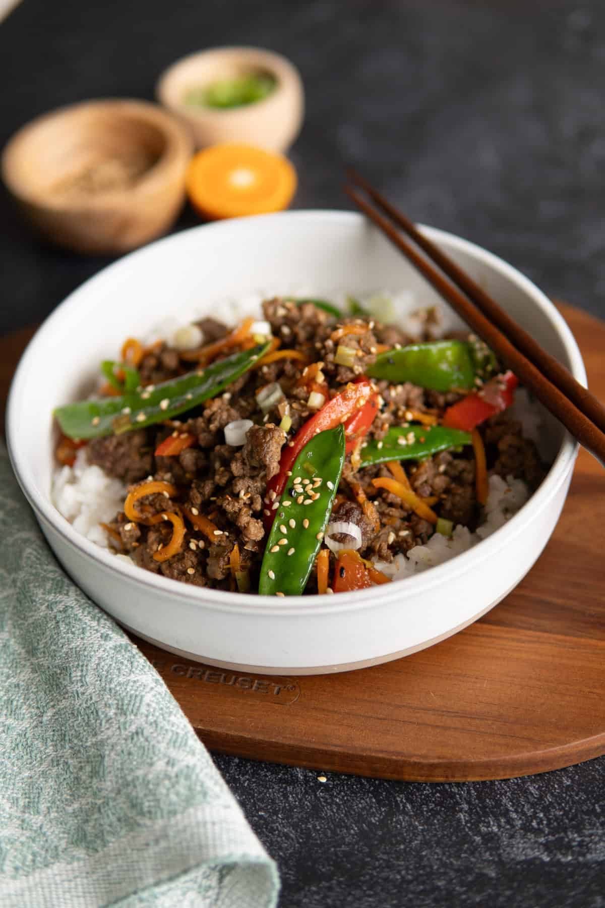 a bowl of ground beef stir fry with chop sticks on top 