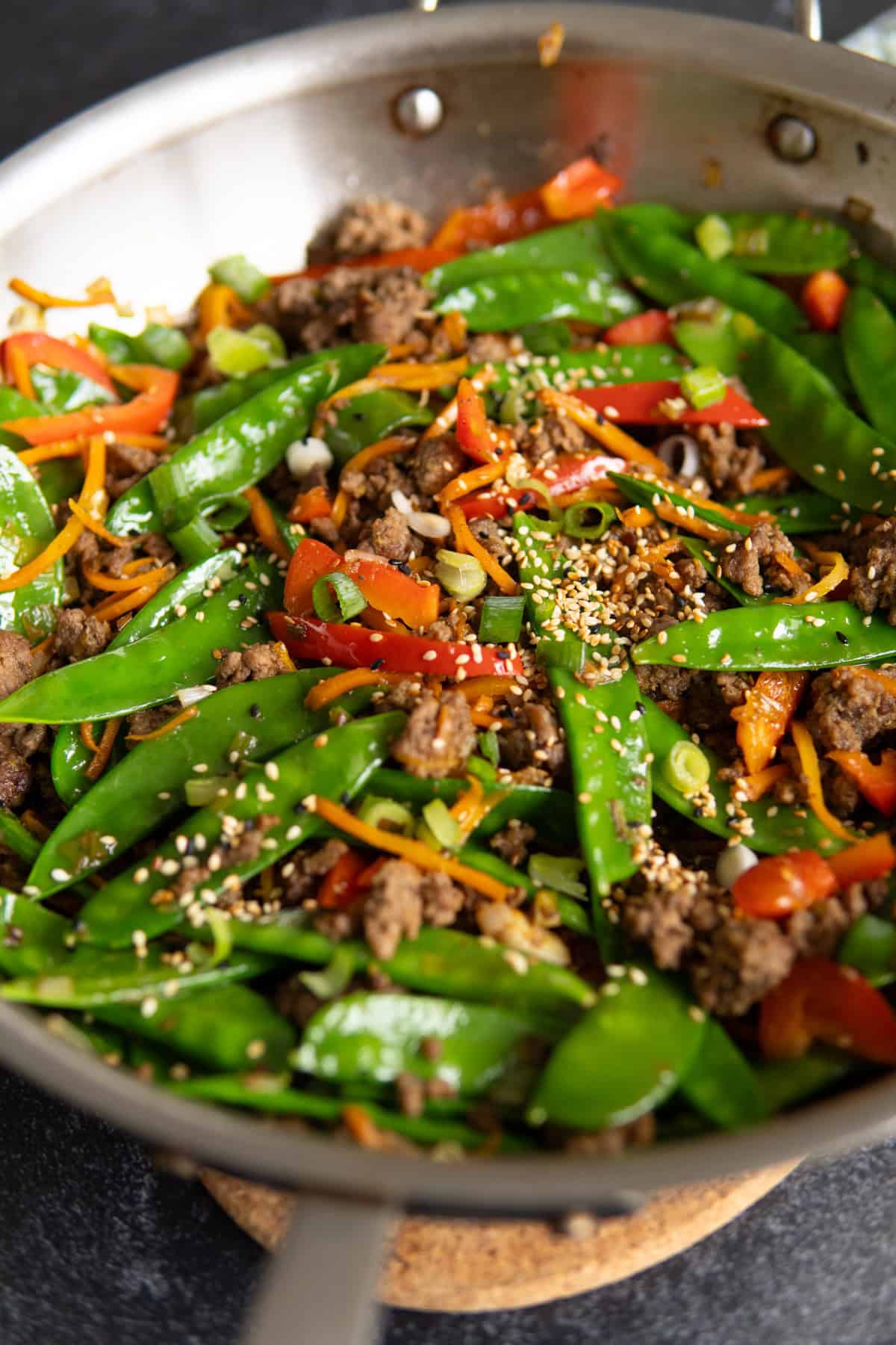 zoomed in shot of ground beef stir fry and snow peas. 