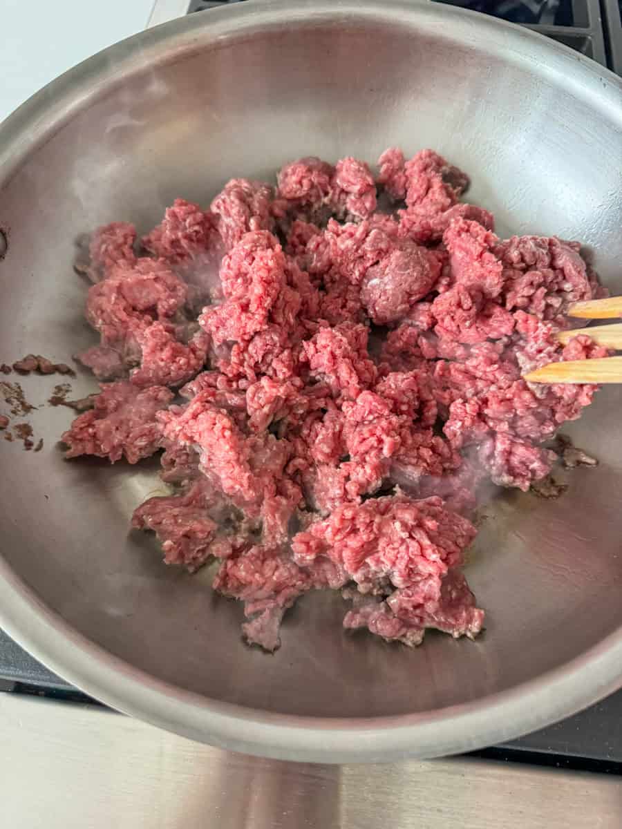 a stainless steel pan with ground beef  sauteing 