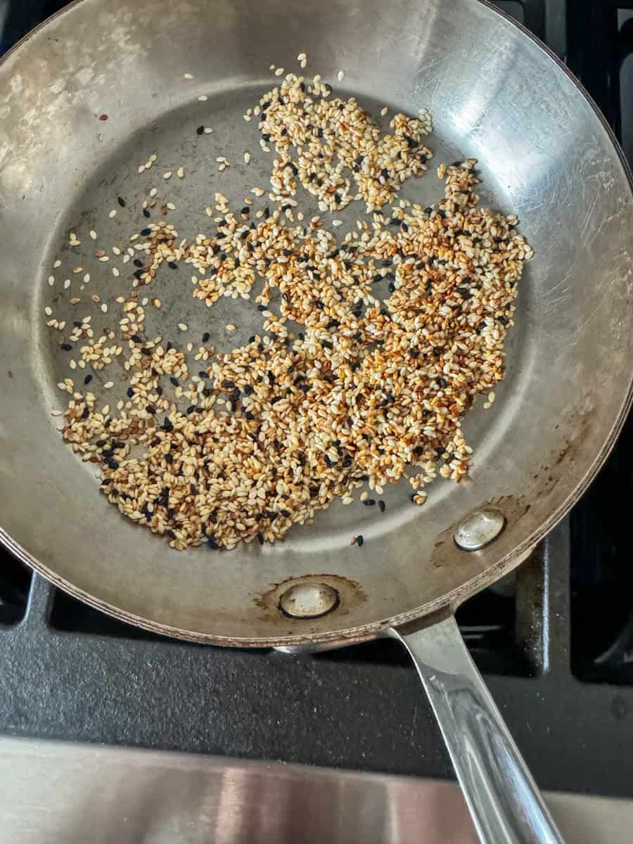 stainless steel pan with sesame seeds being toasted. 