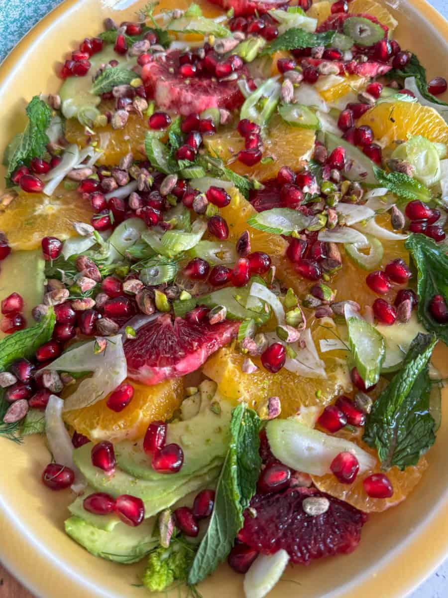 close up of salad on a platter, bright colors from oranges, pomegranate seeds and mint. 