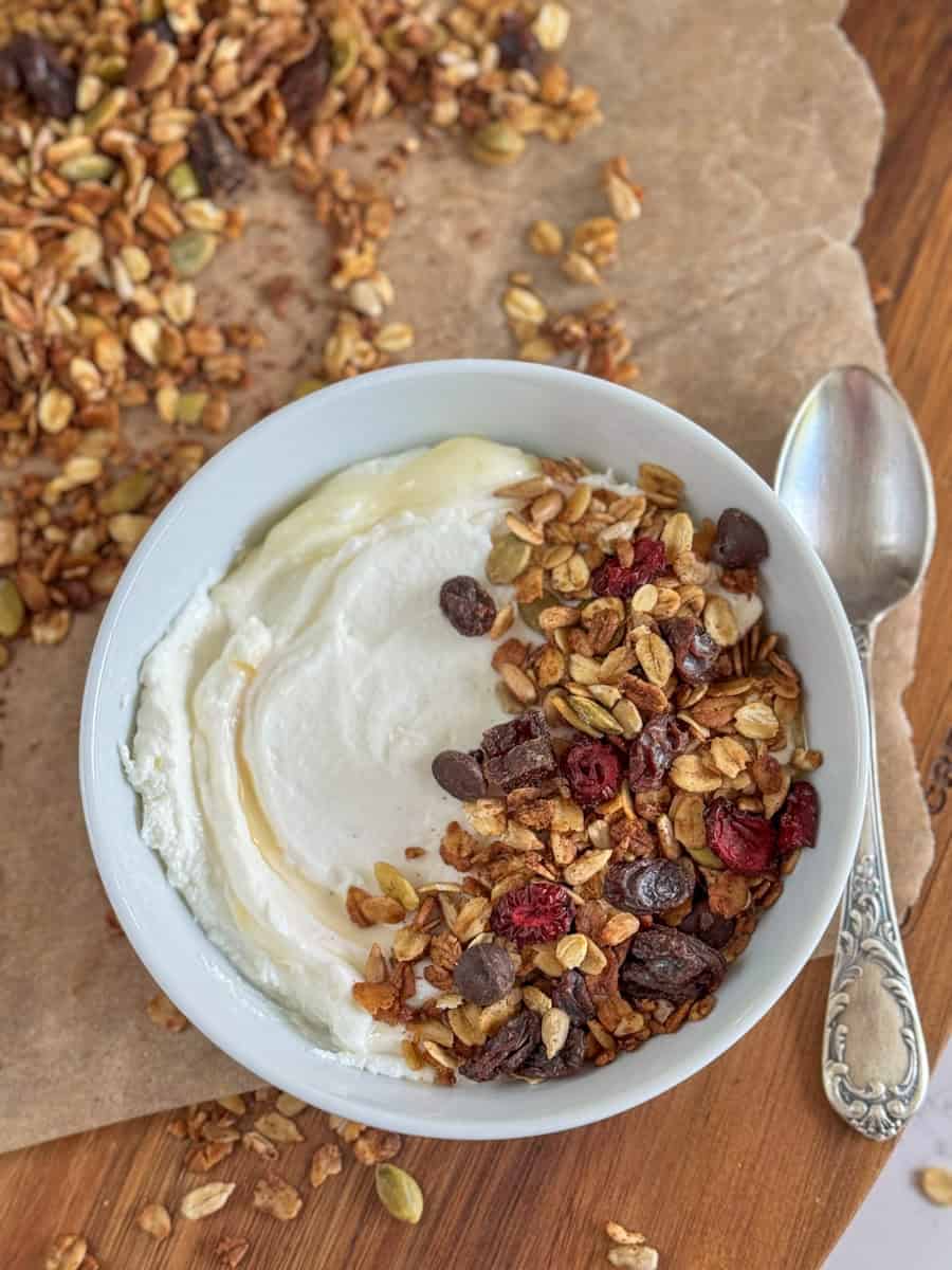 bowl with yogurt, honey, and granola sprinkled on side. 