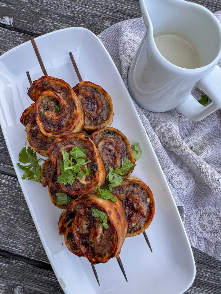 plate with beef roll-ups and a side of tahini dressing 