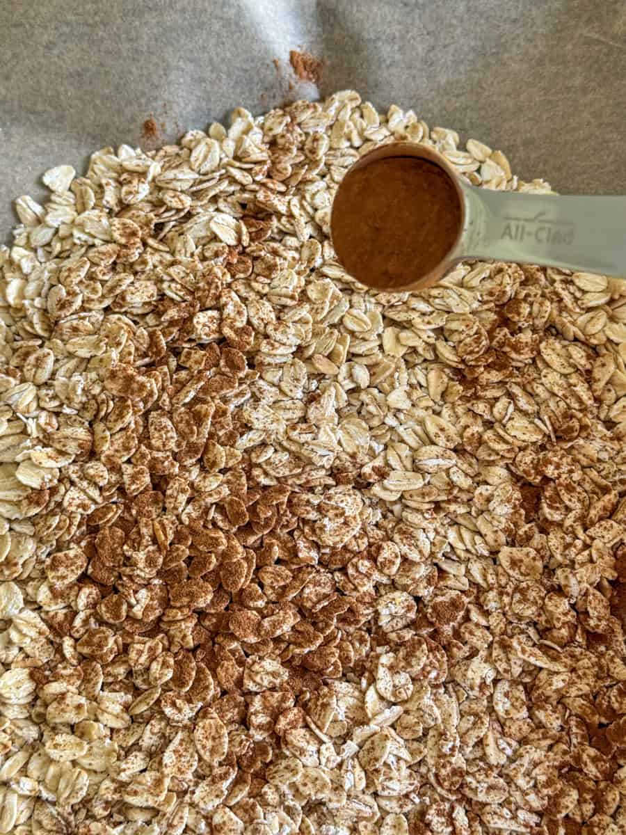 oats spread on baking sheet with cinnamon sprinkled. 
