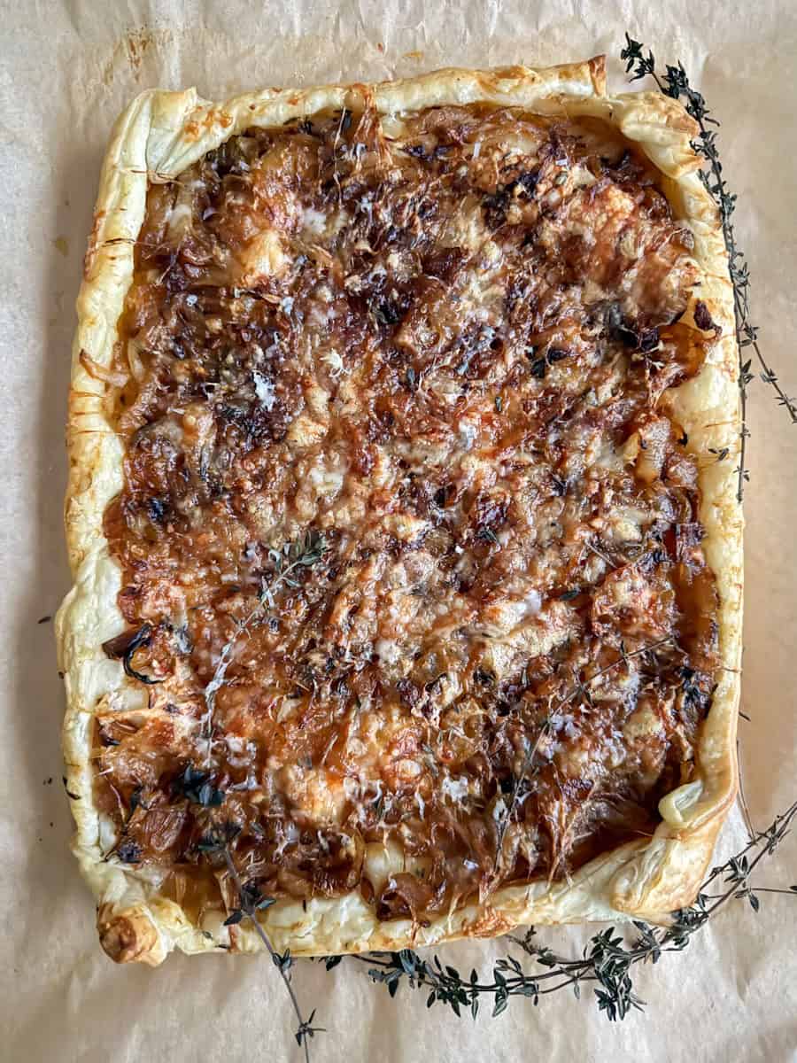 baked puff pastry with caramelized onions and gruyere cheese on parchment paper