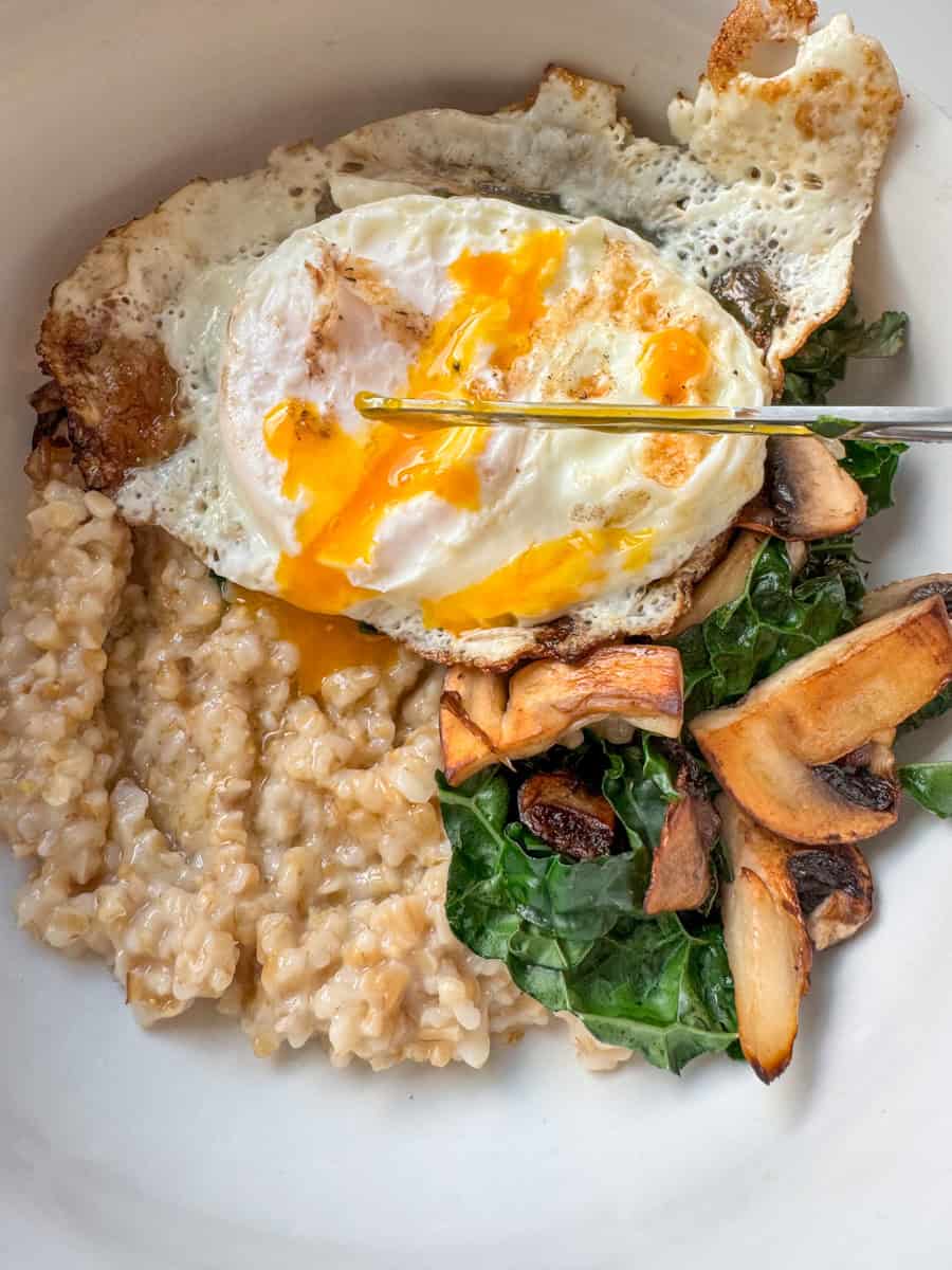 bowl with steel cut oats, kale, mushrooms, and runny egg.