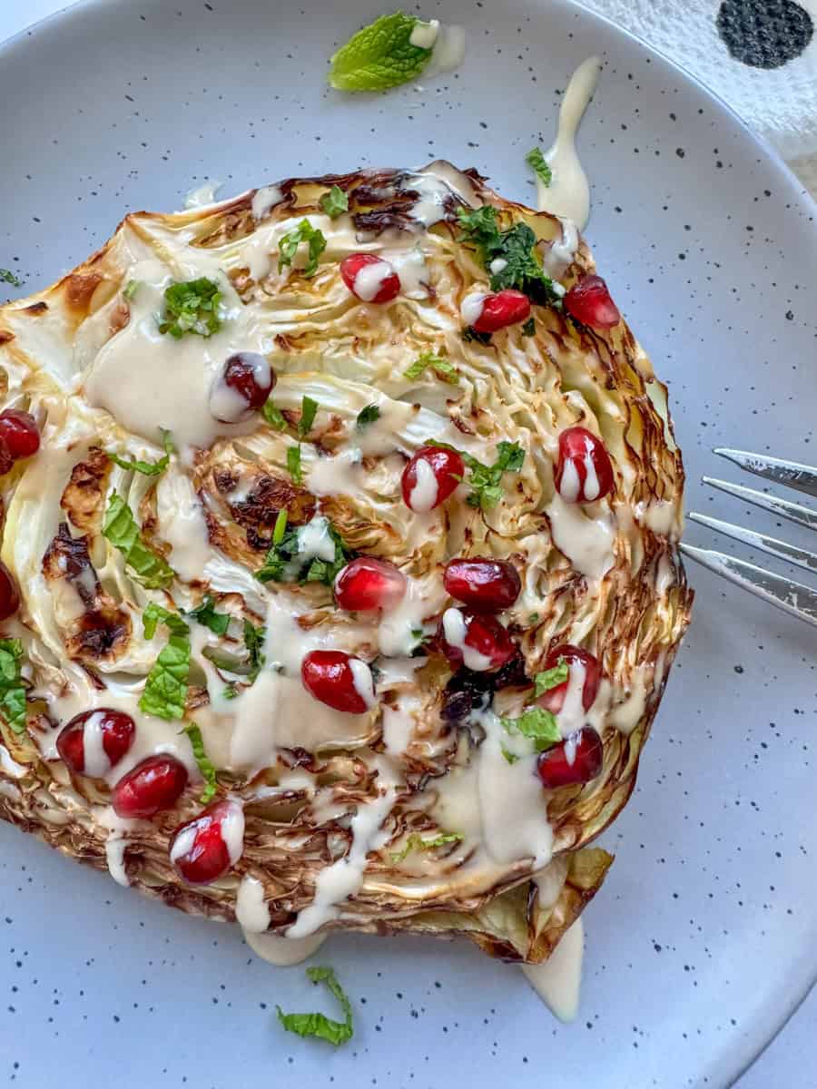 roasted cabbage steak drizzled with tahini and sprinkled with pomegranate seeds 